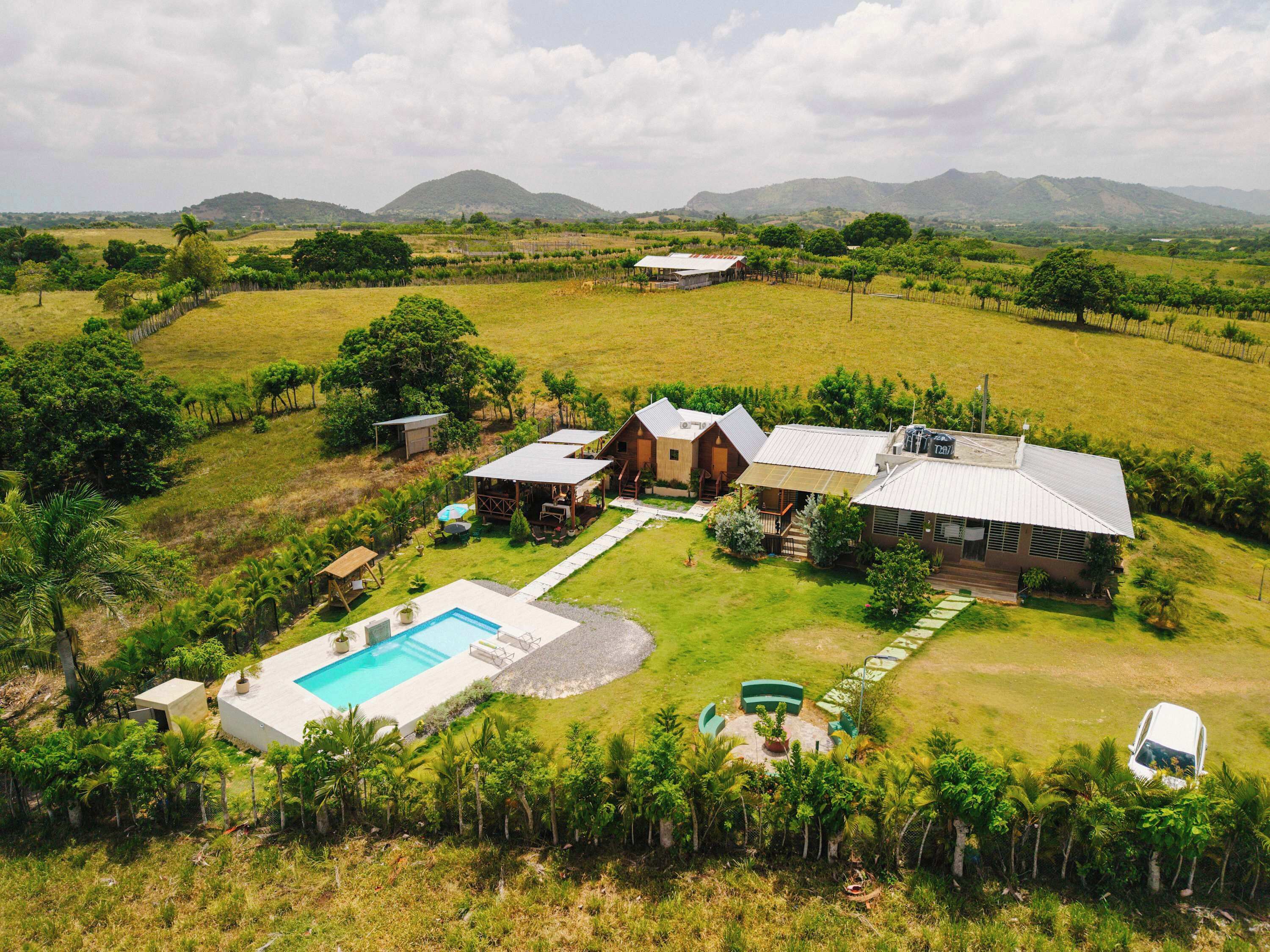 Propiedad rural con piscina, varias construcciones y abundante vegetación.