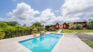 A rectangular swimming pool with a tiled edge, surrounded by a wooden deck. - Villa Campestre by Otium (Higuey)