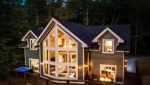 Una casa de dos pisos con un amplio ventanal, una terraza y una chimenea.