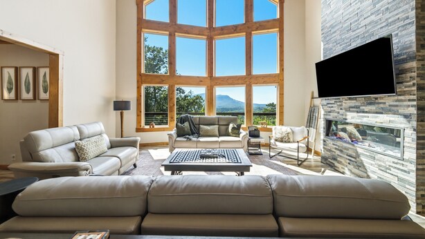Un salón espacioso con un gran ventanal, chimenea y televisor de pantalla plana.