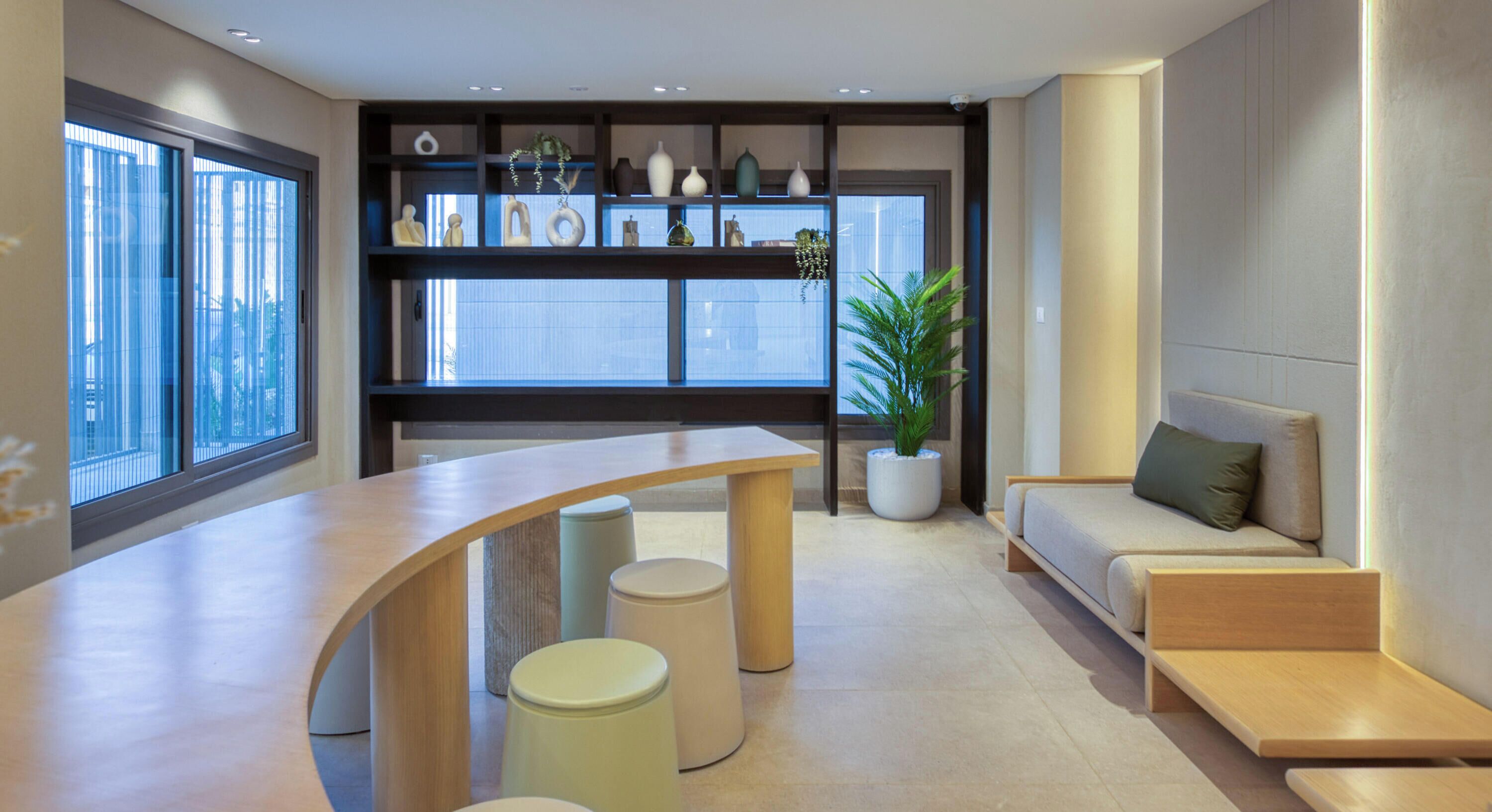 Un interior moderno con un mostrador de recepción curvo, una zona de estar y una planta.