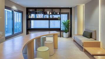 Un interior moderno con un mostrador de recepción curvo, una zona de estar y una planta.