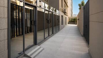 Um corredor com portas de vidro, piso ladrilhado e fachada de edifício.