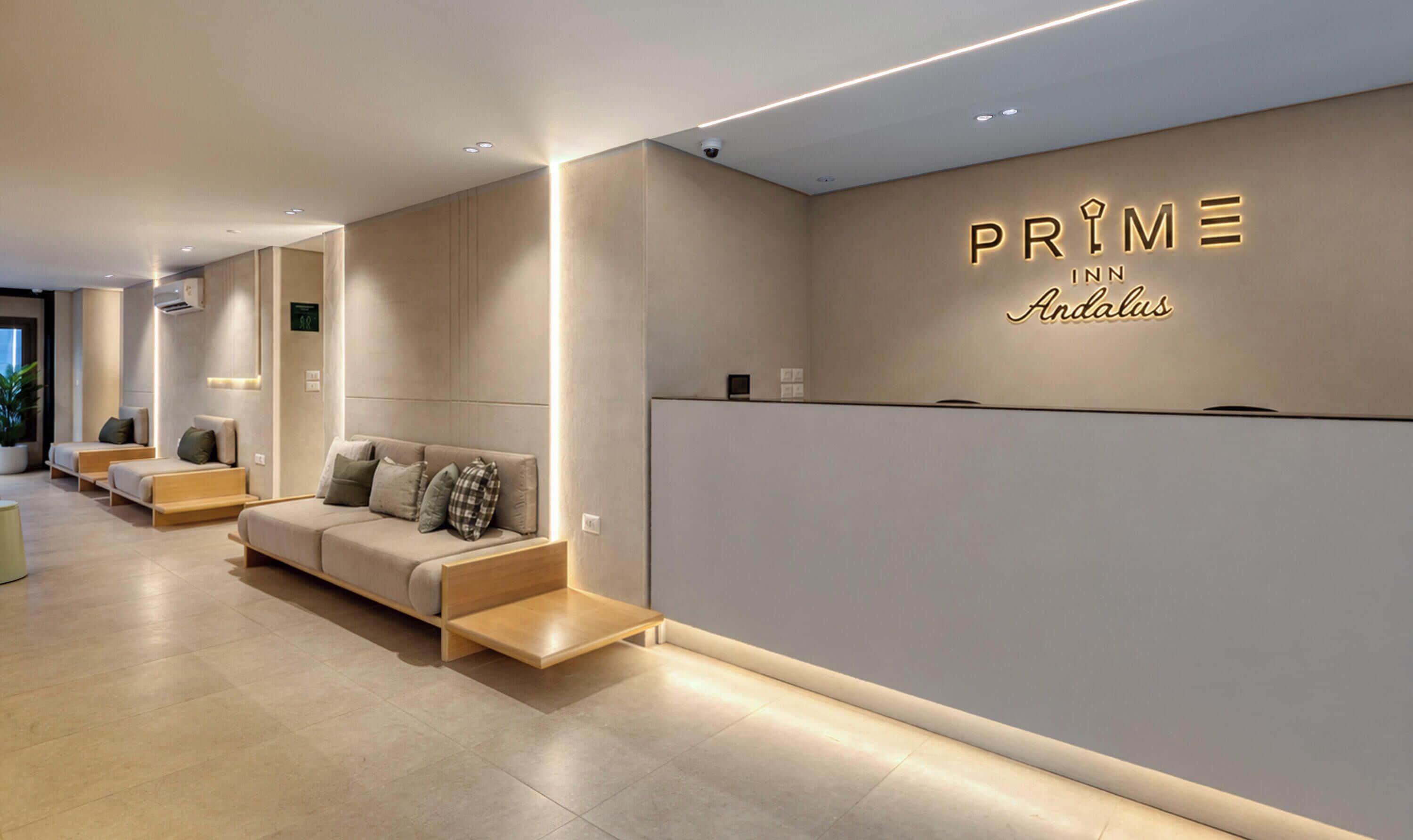 A modern hotel reception area with a sofa, a reception desk, and a wall with the hotel name.