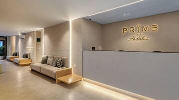 A modern hotel reception area with a sofa, a reception desk, and a wall with the hotel name.