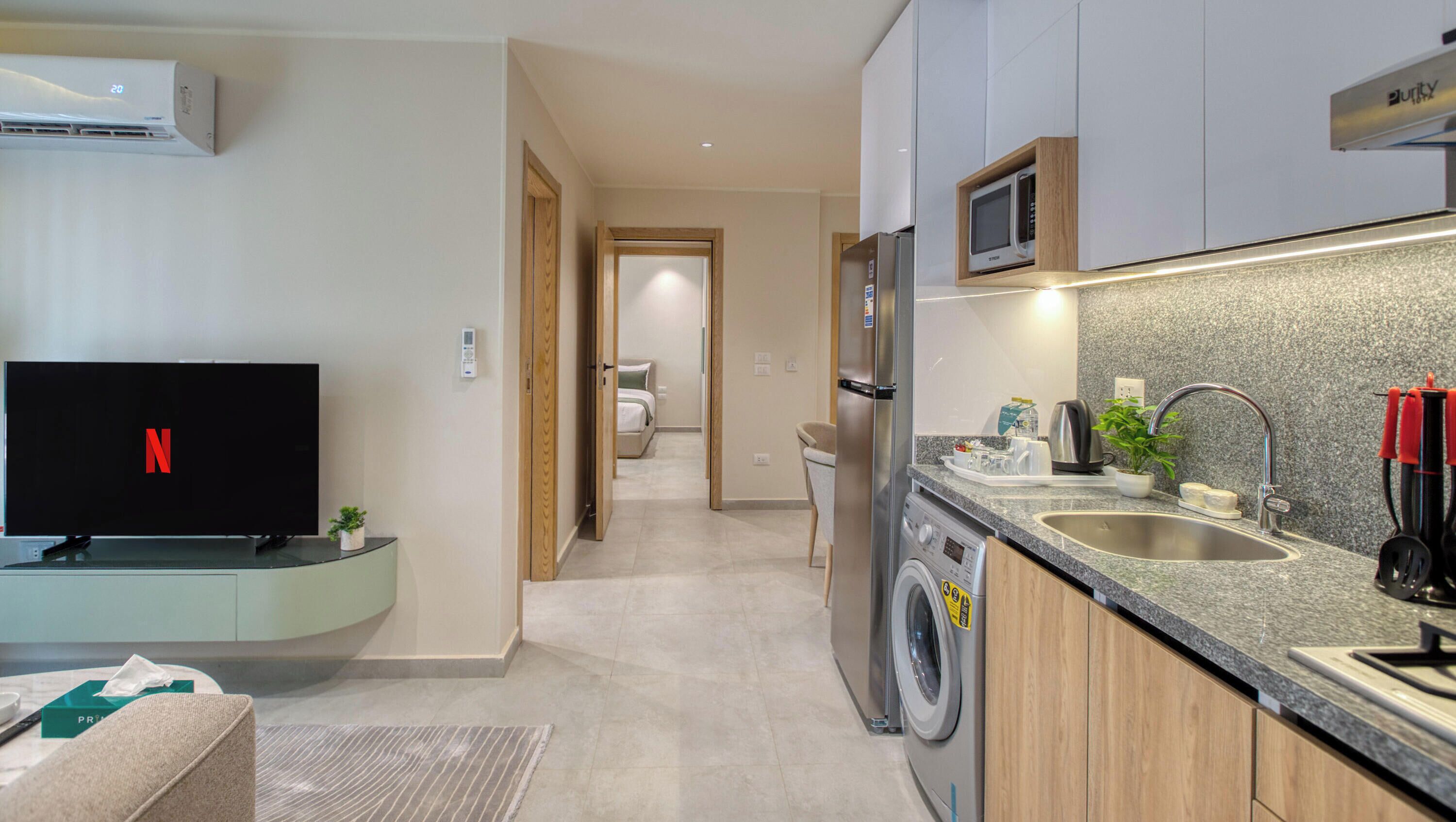 A modern kitchen with a built-in microwave, stainless steel sink, and a washing machine.