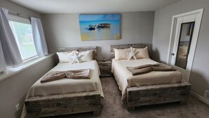Ein Schlafzimmer mit zwei Holzbetten, einem Bild von Booten an der Wand und einer Tür rechts.