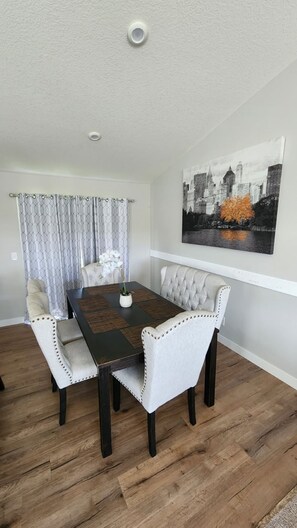 A dining area with a table, chairs, and a cityscape painting. - Pet-Friendly Faribault Home • Near Shattuck-St. Mary's (Faribault)