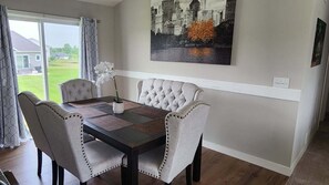 A dining area with a table, chairs, and a cityscape painting on the wall.