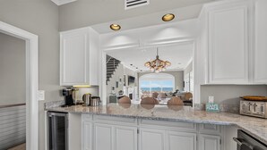 A kitchen with white cabinetry, a central island, a built-in refrigerator, and a view to a dining area. - Ocean Front, Updated 4 Bedroom, 3.5 Bath (St. Simons Island)