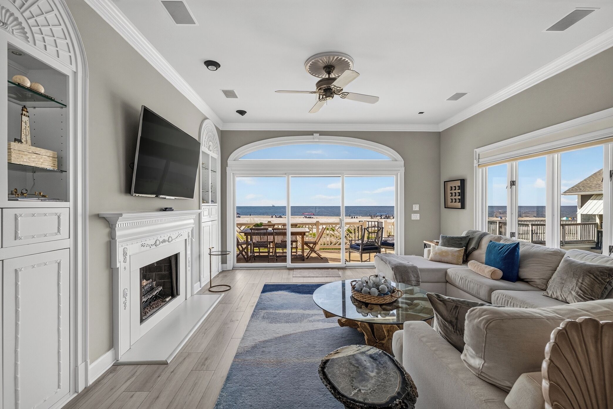 A living room with a fireplace, a television, a large window, and a balcony with outdoor furniture.