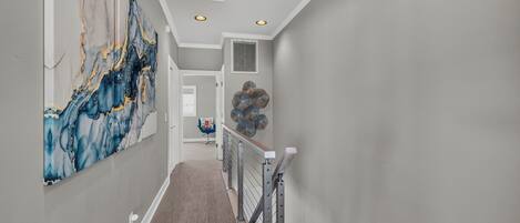 Un couloir orné d’un décor mural en marbre, avec un escalier et un élément décoratif mural.