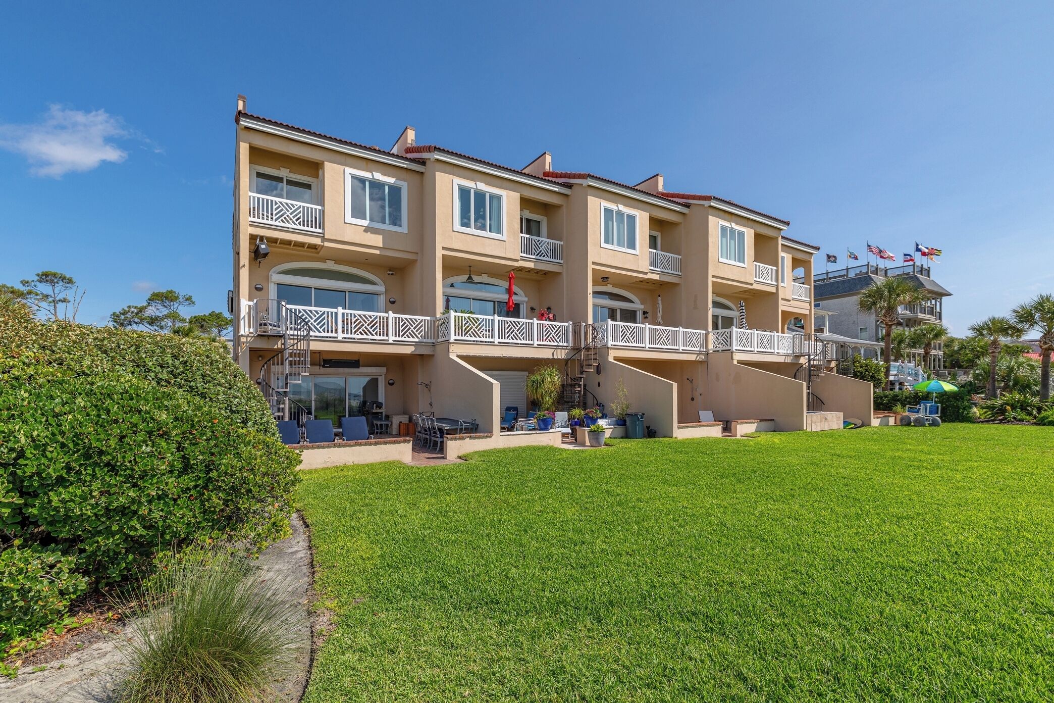 A multi-story hotel with balconies, a well-maintained lawn, and a clear blue sky.