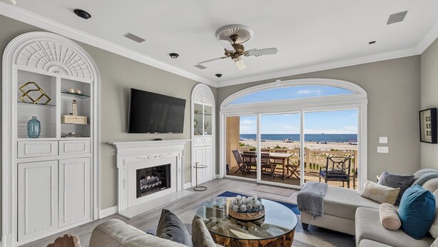 A living room with a fireplace, television, and a view of the beach. - Ocean Front, Updated 4 Bedroom, 3.5 Bath (St. Simons Island)