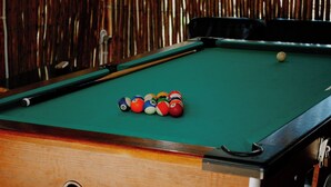 Une table de billard recouverte d’un drap de feutre vert et comprenant un jeu de billes numérotées.