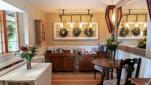 Una cocina con armarios de madera, una encimera blanca, una mesa de comedor con sillas y una ventana con vistas.