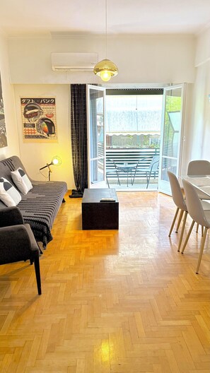 Ein modernes Wohnzimmer mit Sofa, Couchtisch, Essbereich mit Stühlen und einem Balkon mit Blick.