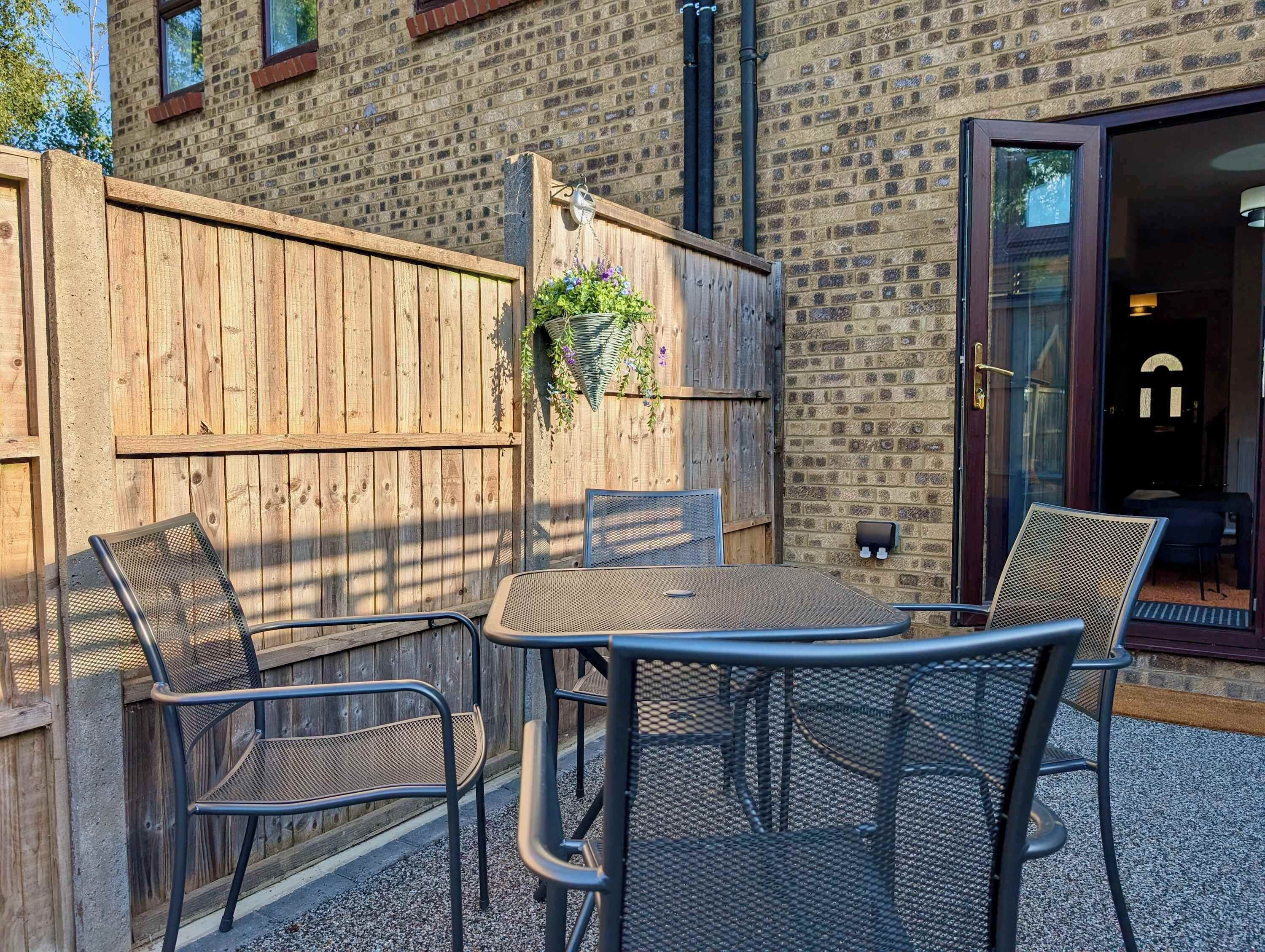 Eine Terrasse im Freien mit Holzlattenzaun, einem Tisch und Stühlen.