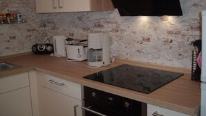 A kitchen with a black induction cooktop, a coffee maker, a toaster, and a radio. - Maria Vacation Rental 3 – Cozy, Central, and Ideal for Families (Wernigerode)