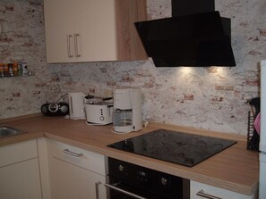A kitchen with a black induction cooktop, a coffee maker, a toaster, and a radio. - Maria Vacation Rental 3 – Cozy, Central, and Ideal for Families (Wernigerode)
