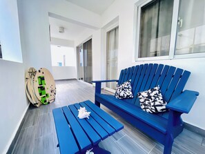 A blue bench with patterned cushions, a surfboard, and a starfish on a tiled floor.