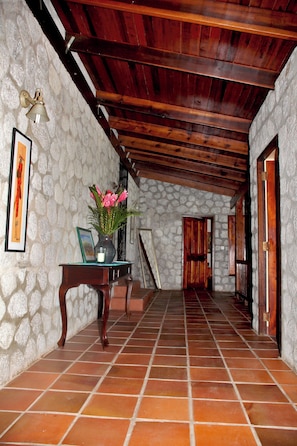 A hallway with stone walls, wooden beams, and tiled flooring.