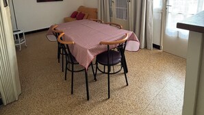 Un coin repas avec une table et des chaises, un tableau au mur, une fenêtre avec des rideaux et un appareil de climatisation.