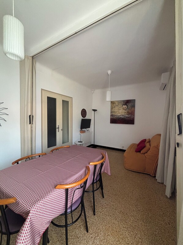 A dining area with a table and chairs, a sofa, a painting, and a door.