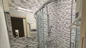 Une salle de bain avec une douche à parois de verre, un lavabo avec un miroir et un porte-serviettes.