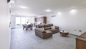 Uma sala de estar moderna com sofá, mesa de centro e um espaço de jantar com cadeiras e mesa.