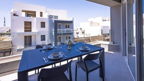 Varanda com mesa posta para refeições, com vista para edifícios modernos.