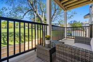 A covered outdoor area with wicker furniture, a wooden deck, and a view of a grassy yard. - New 3 bedroom, 2 bath unit, meadow view! (Boston)