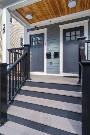 A set of wooden steps leading to a front door with a mailbox and a fire hydrant. - New 3 bedroom, 2 bath unit, meadow view! (Boston)