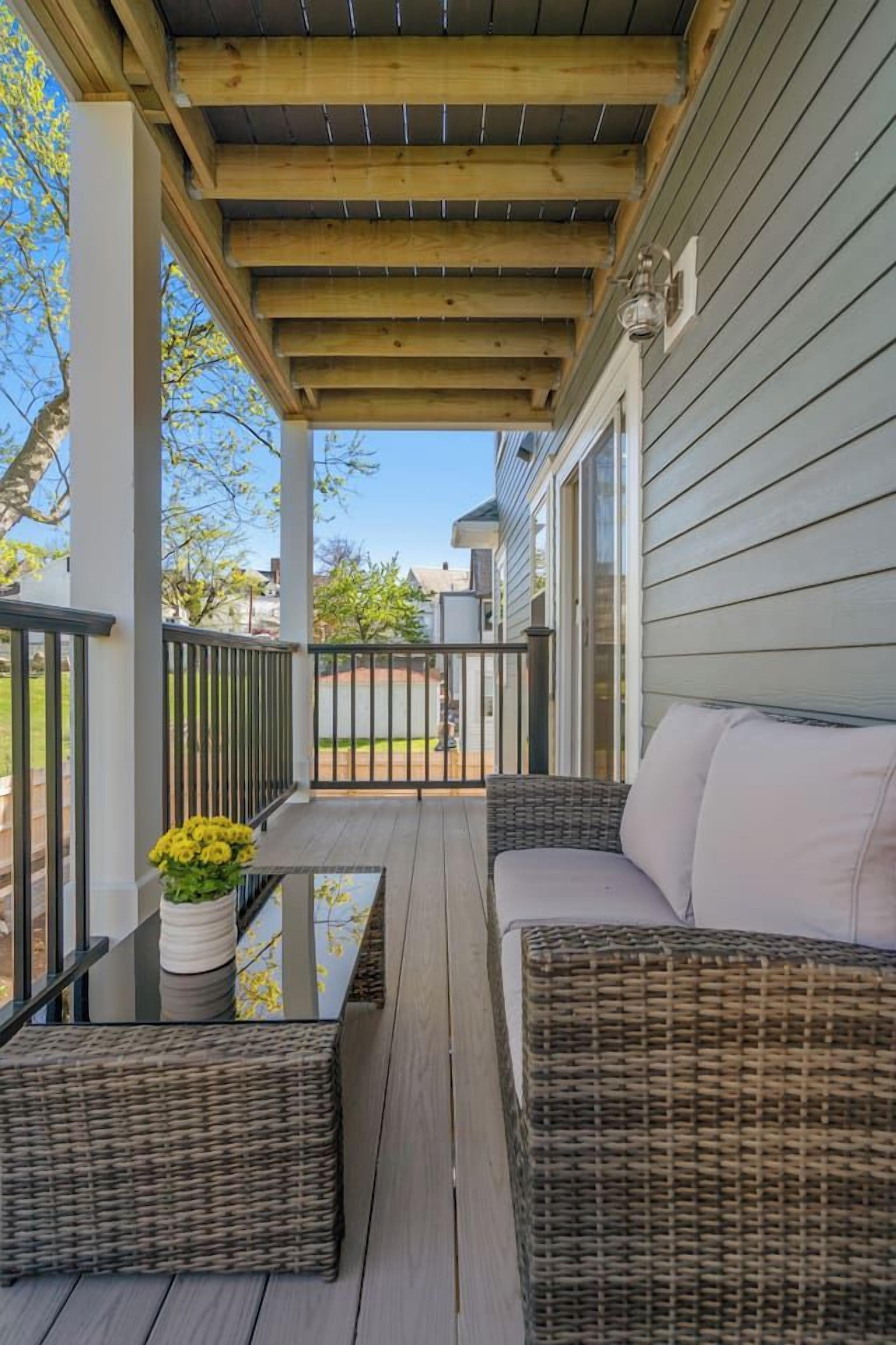 A covered porch with wicker furniture and a potted plant.