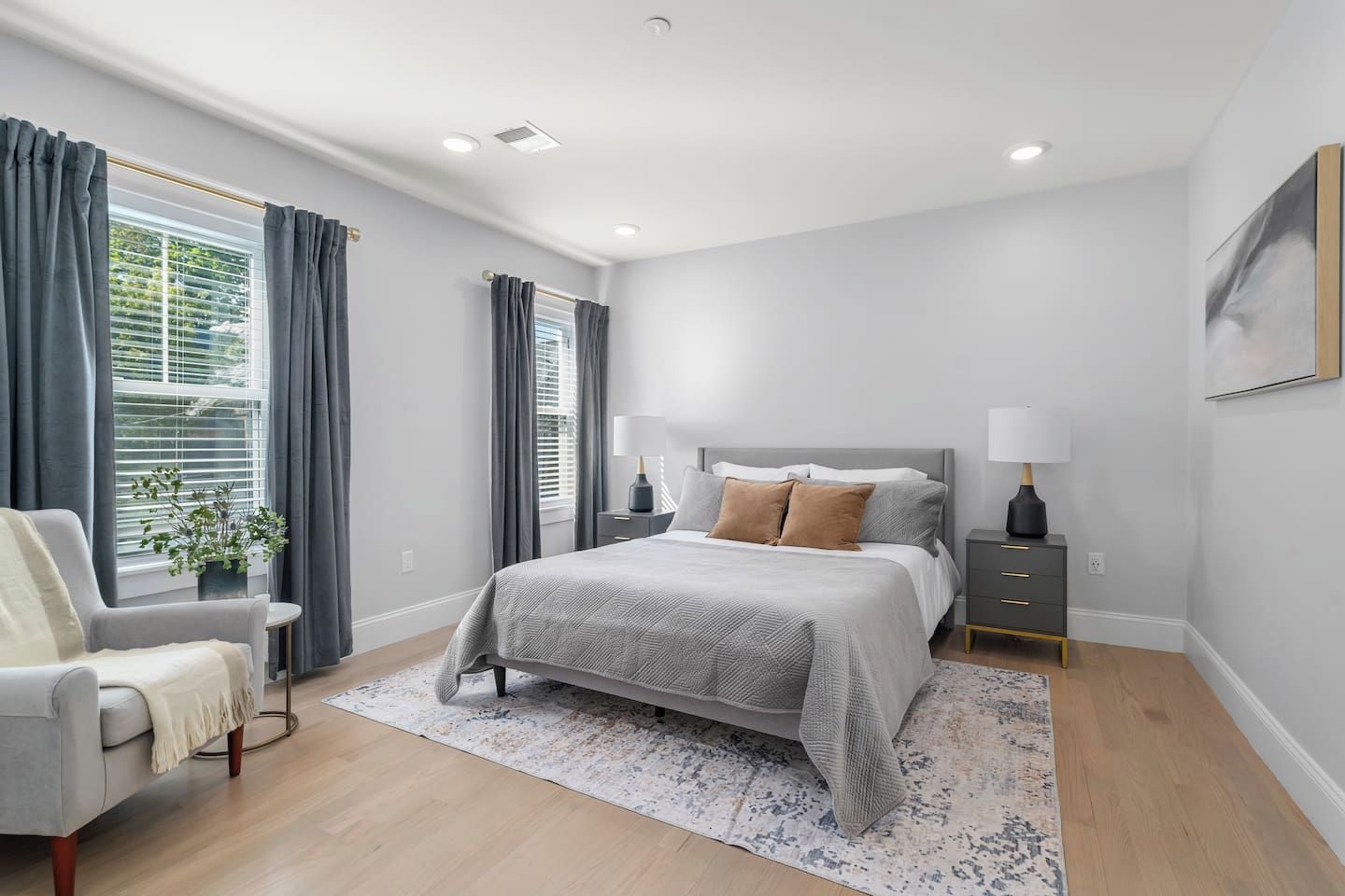 A bedroom with a bed, bedside tables, a chair, and a window with curtains.