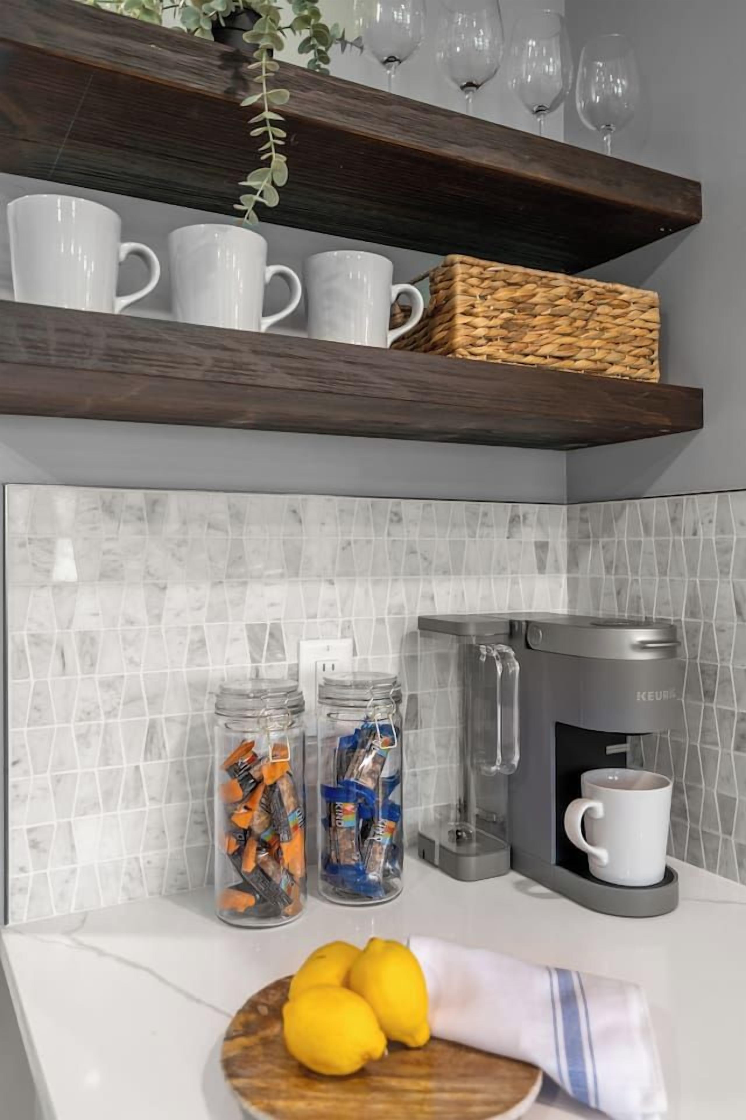 A kitchen with a coffee maker, jars of snacks, and a bowl of lemons on the counter.