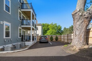 A residential area with a two-story building, a parked car, and a tree.