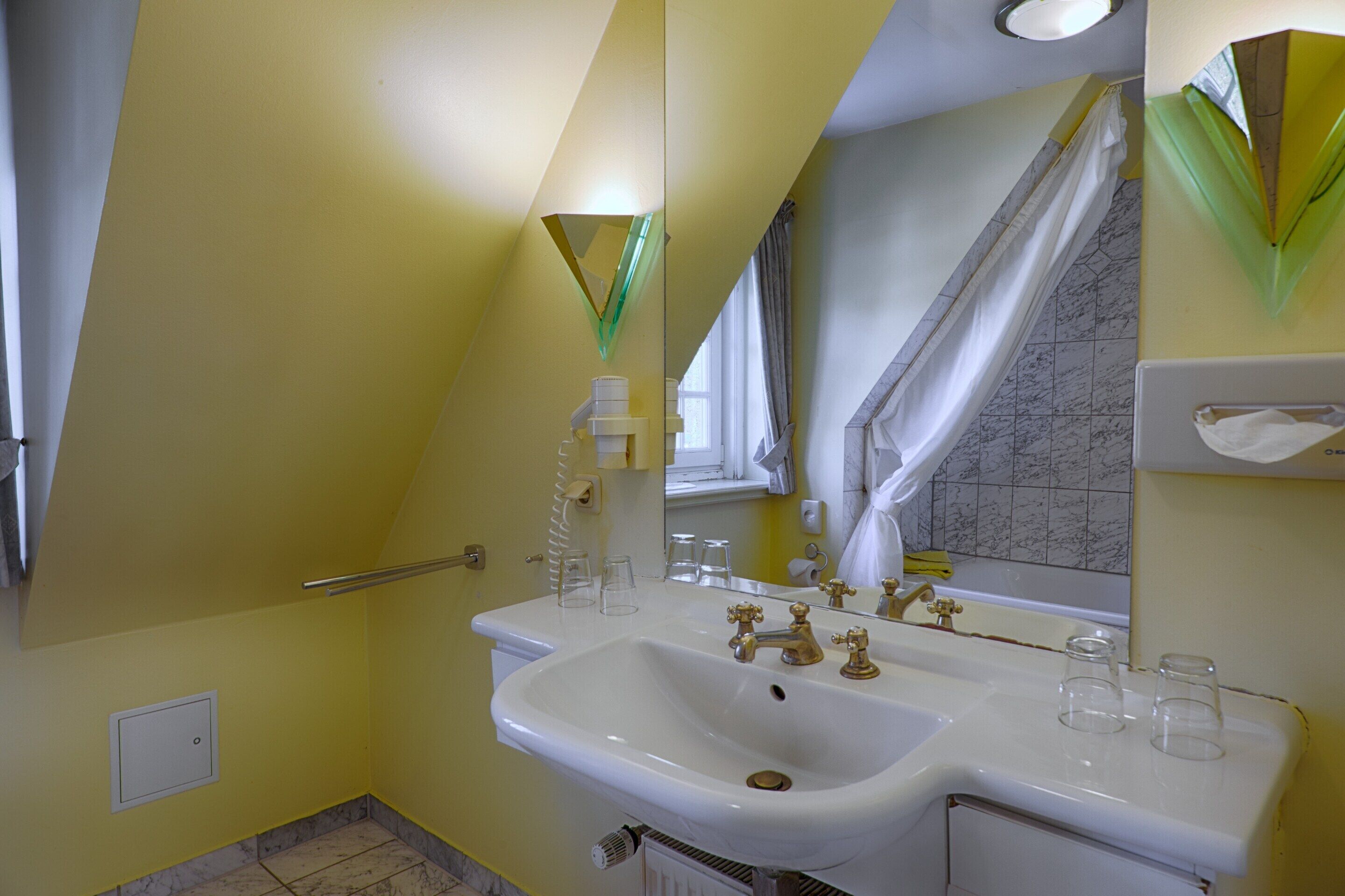 A bathroom with a white sink, a mirror, and a towel rack.