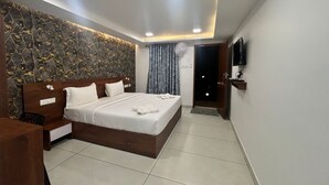 Un dormitorio moderno con cama, mesitas de noche, televisión de pantalla plana y una lámpara en el techo.