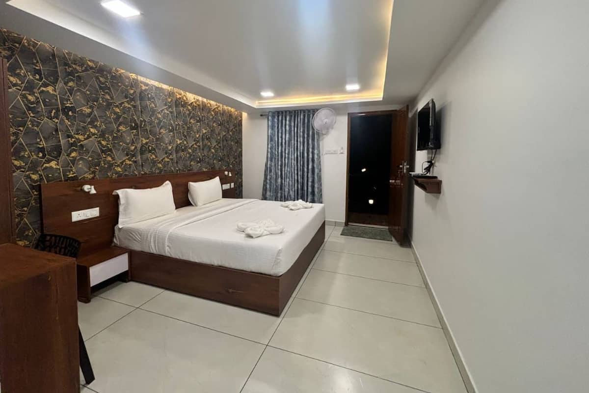 Un dormitorio moderno con cama, mesitas de noche, televisión de pantalla plana y una lámpara en el techo.