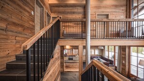 Un interno in legno con una scala, un'area pranzo e una vista attraverso ampie finestre.