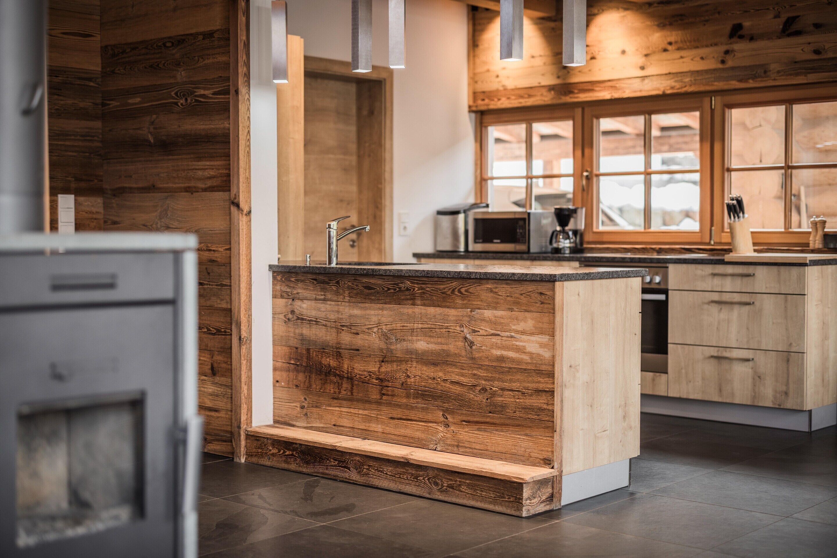 A modern kitchen with wooden accents, a built-in island, and a view through large windows.