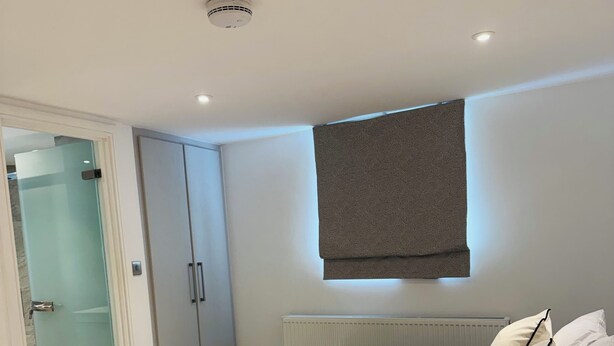Ein modernes Schlafzimmer mit Bett, Nachttisch, Kleiderschrank und einer Duschkabine aus Glas.