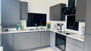 Eine moderne Küche mit grauen Schränken, einer Edelstahl-Spüle und einem eingebauten Backofen.