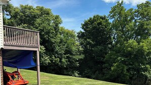 Une pelouse bien entretenue, agrémentée d’une terrasse en bois et d’une tondeuse à gazon rouge.