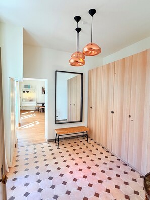Ein Flur mit einem Holzschrank, einer Bank, einem Spiegel und einem Musterboden.