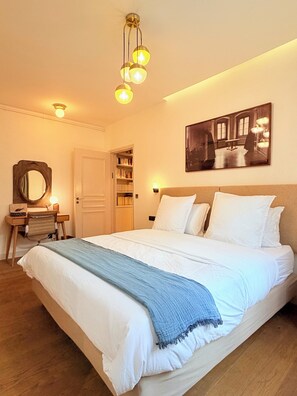 A neatly arranged bedroom with a bed, bedside tables, a desk, a mirror, and a bookshelf. - 3-bedroom 2 bathroom apartment in Le Marais with AC (Paris)