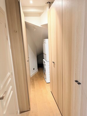 Ein enger Flur mit Holztüren und einer Waschmaschine im Hintergrund.