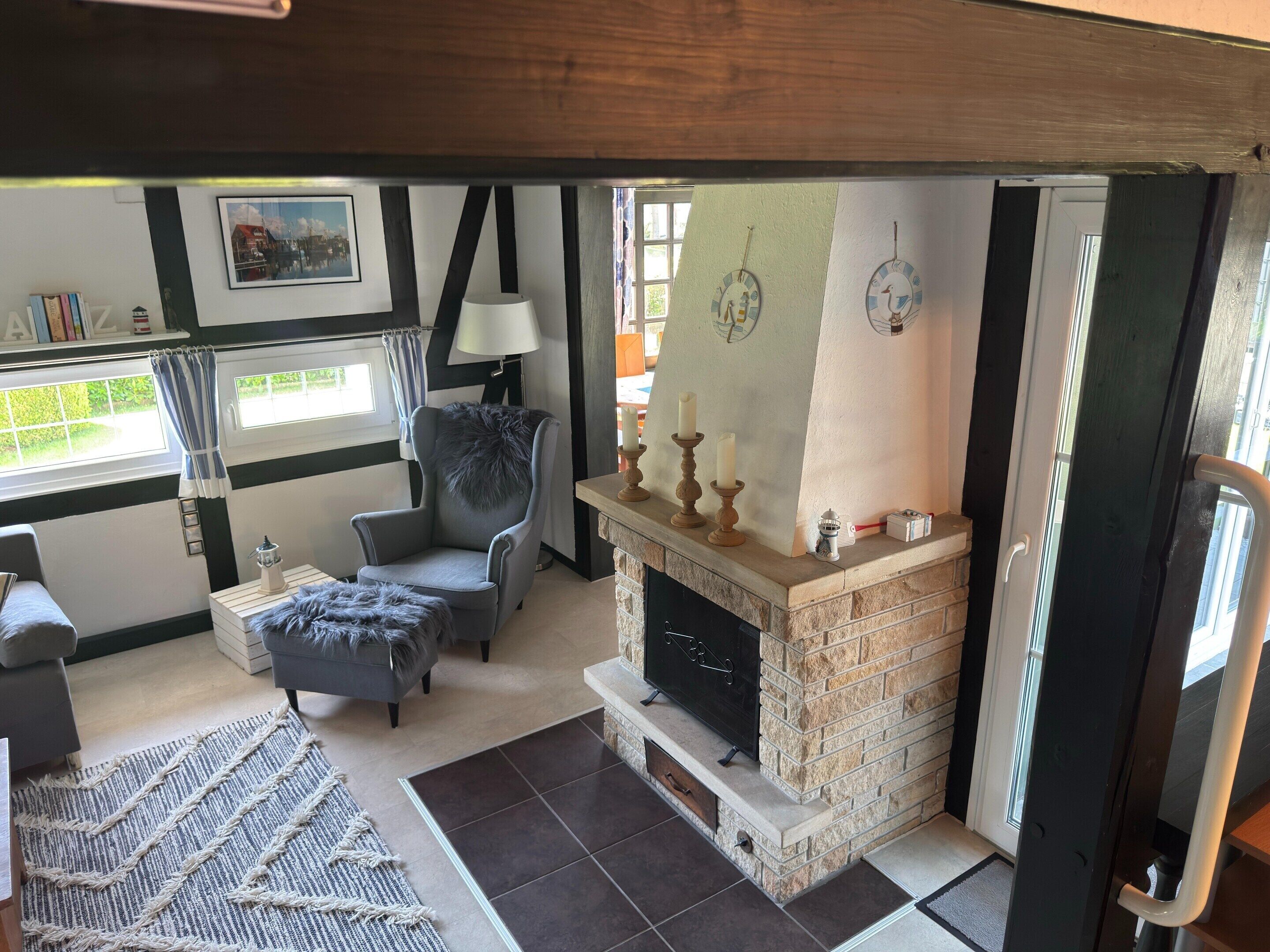 A cozy living room with a fireplace, a comfortable armchair, a lamp, and a view of the outside.