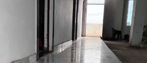 A corridor with a shiny marble floor, leading to a room with a large window.